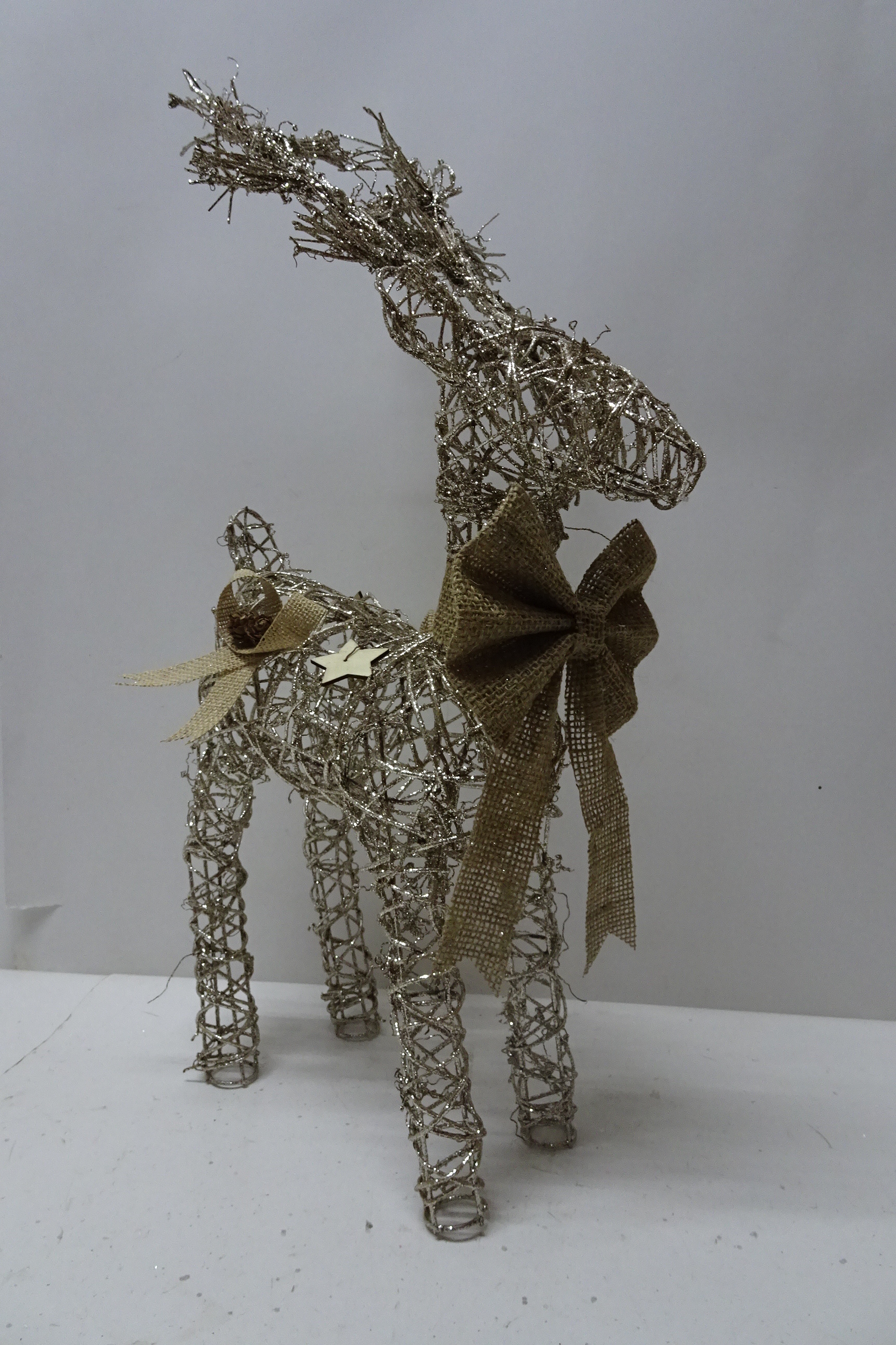 Rattan reindeer with burlap bow and wooden star decoration.